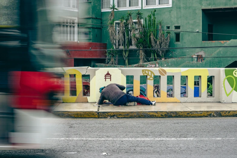 a person sitting on a curb next to a building