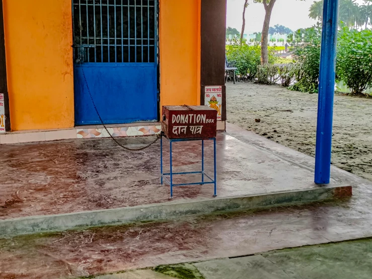 a small sign stands in front of an orange and blue building