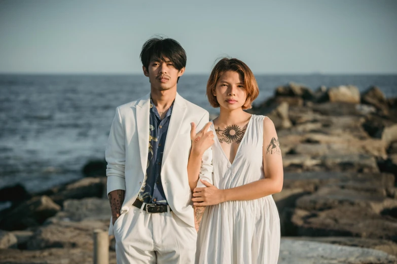 a man and woman standing in front of the ocean