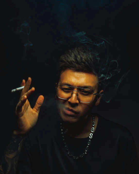 a man smoking in the dark with shades on his face
