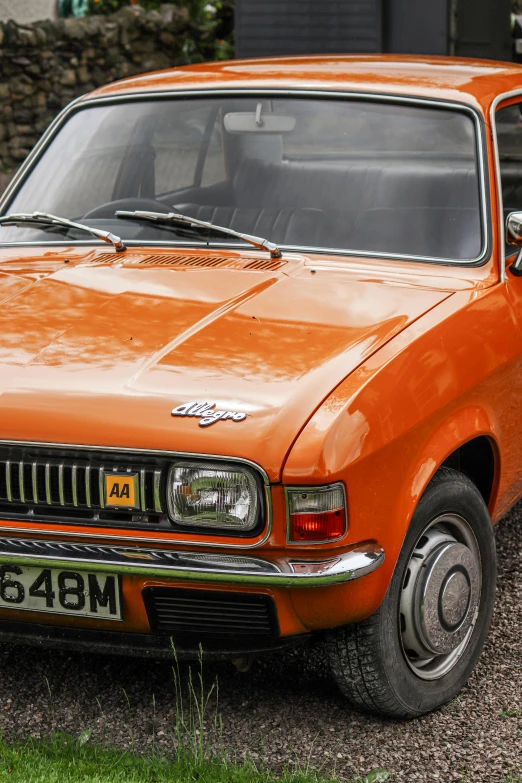 an orange ford falcon sports car is parked in front of a stone wall