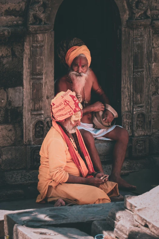 two men sitting near each other next to a building