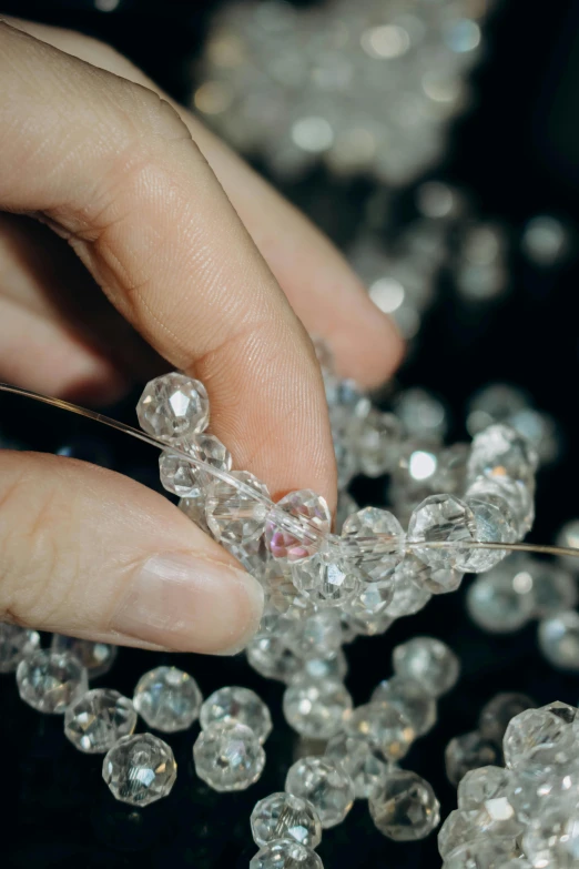 the hand is holding crystal beads on a black surface