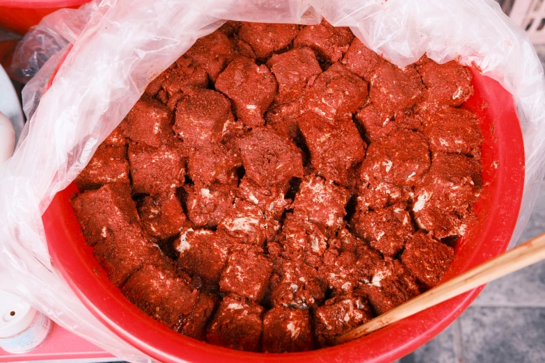 a red bowl holds some food and chop sticks