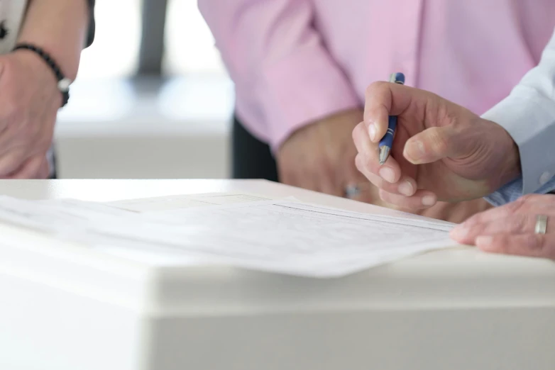 two people with pens are at a white table