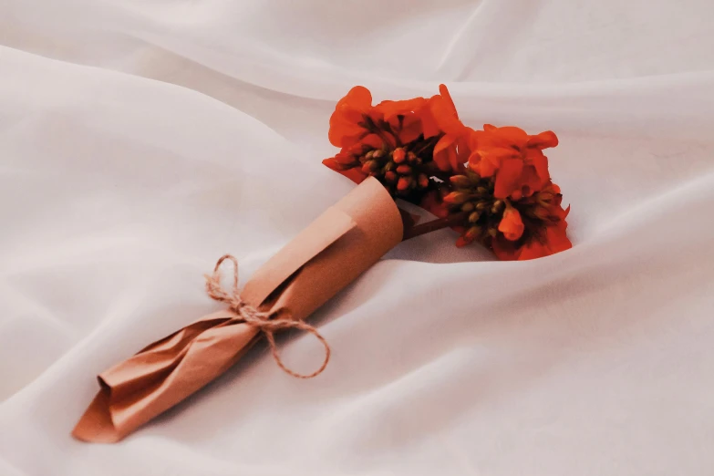 a red flower is lying on top of a white sheet