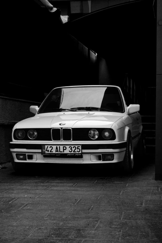 a white car parked in a garage by some stairs