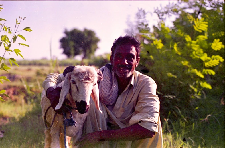 a man is holding a lamb in a field