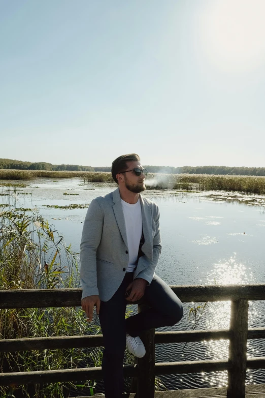 a man standing on a wooden fence next to a body of water