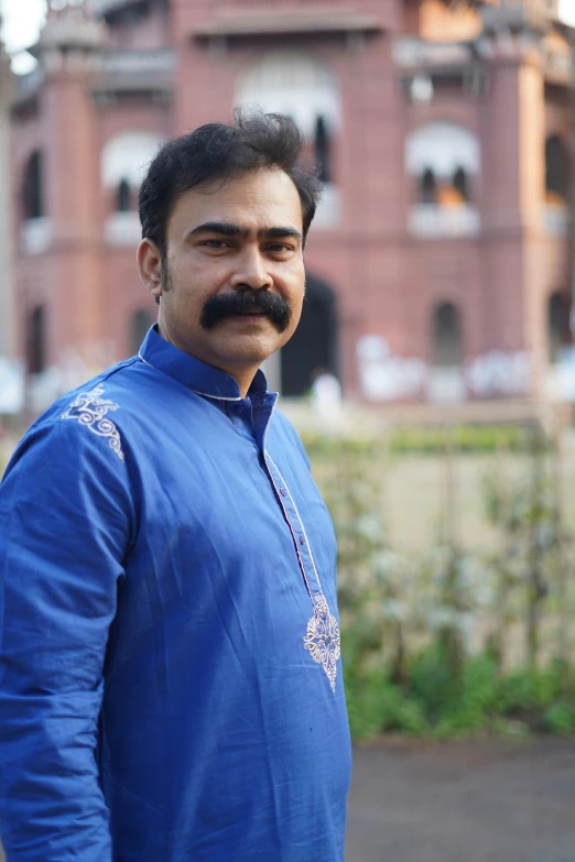 a man in a blue dress shirt standing next to a building