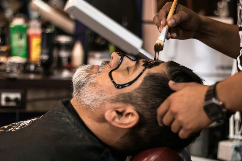 a man getting his hair cut at a barber shop