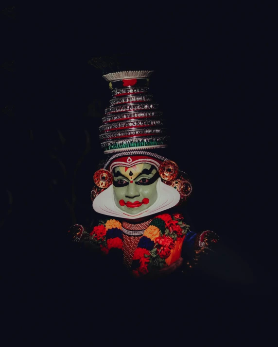 a colorful, elaborately dressed clown head in the dark