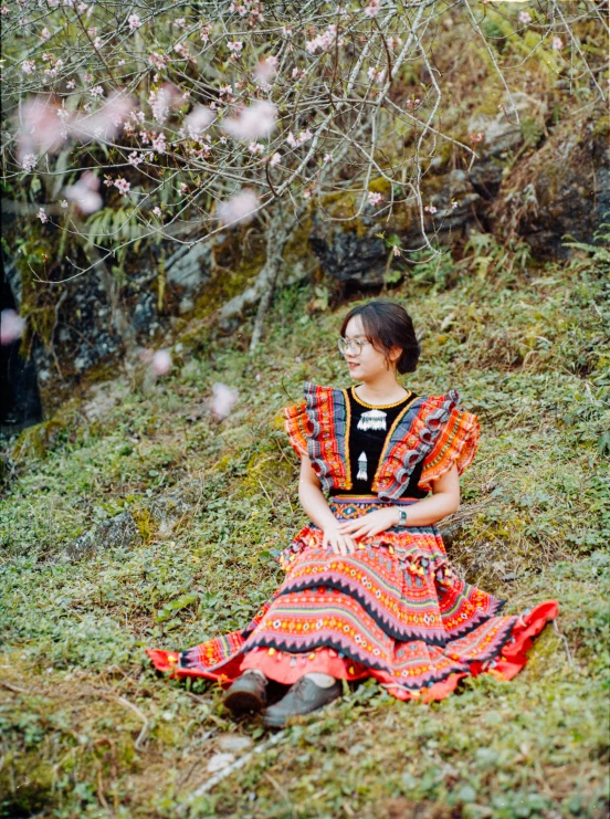 a woman sitting in the grass with flowers around her