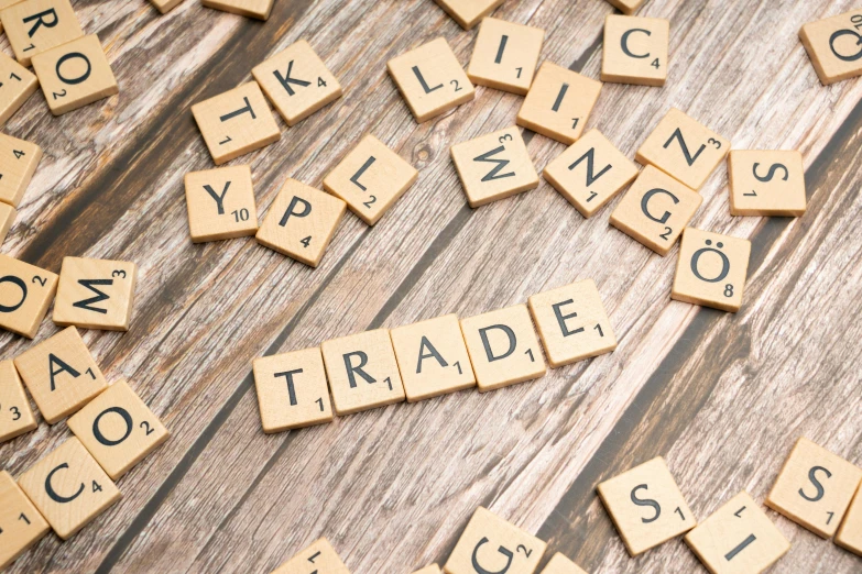 scrabble letters spelling trade and price on a wooden table