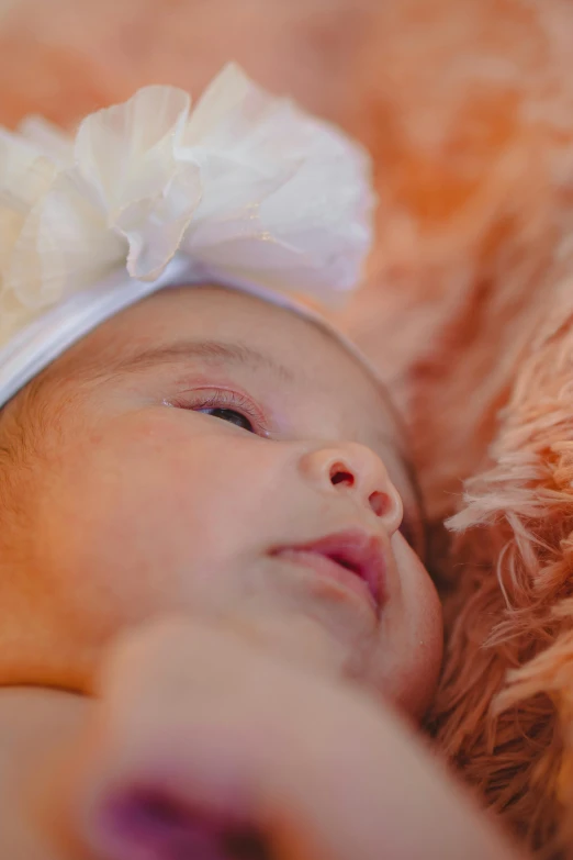 a baby girl has her head tilted, in a blanket