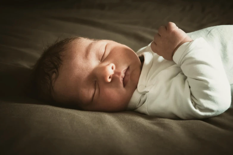 a baby laying on top of a brown bed