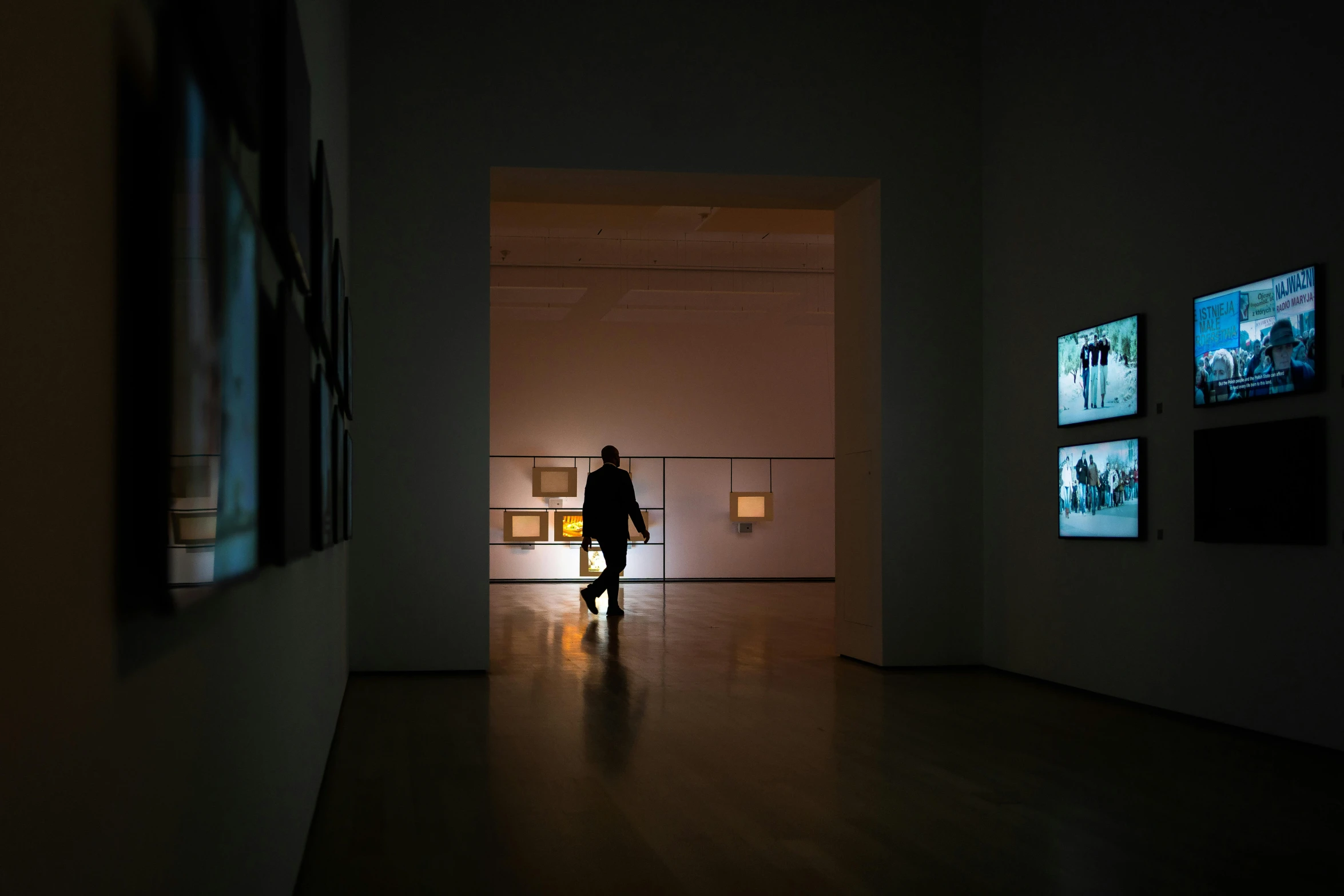 a person walks through a dark tunnel with several framed pos