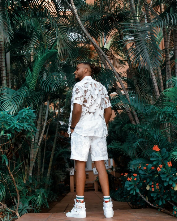 a man standing in front of trees with a lot of tropical vegetation