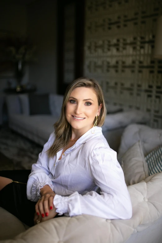 a beautiful young lady sitting on top of a white bed