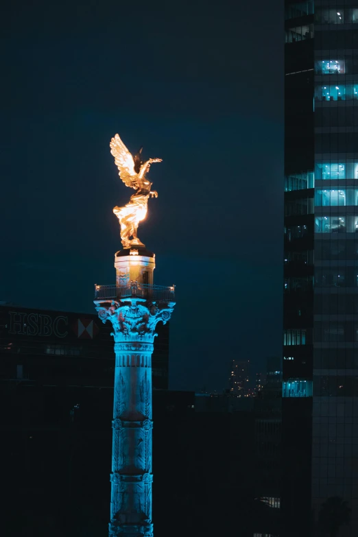 a tall building with an eagle statue and lights on