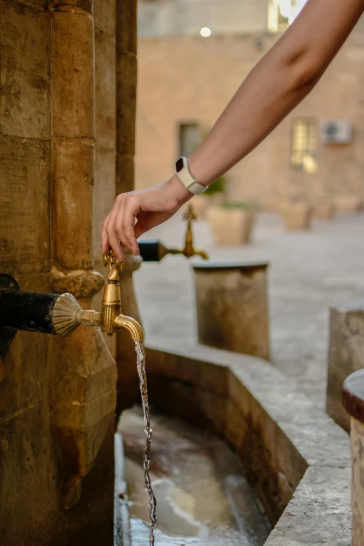 a woman reaches out from a hand that is holding a fountain