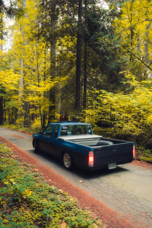 an old pick up truck drives down a gravel road