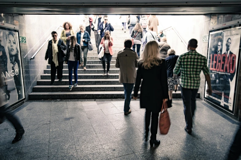 a woman walking up some stairs while holding a hand bag