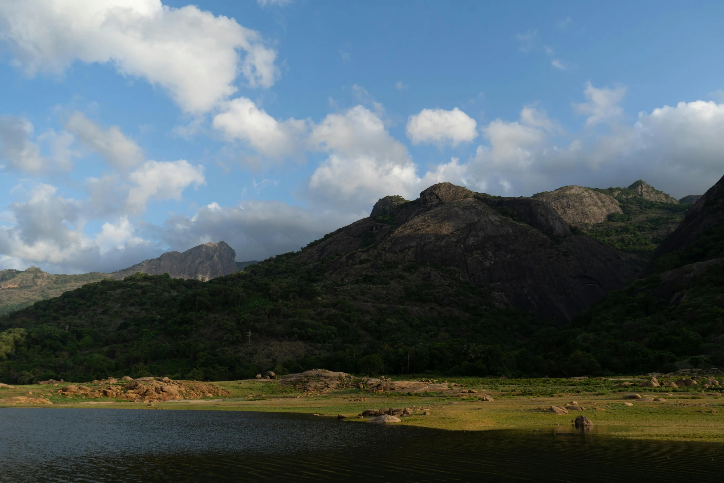 a small lake in front of a rocky mountain range