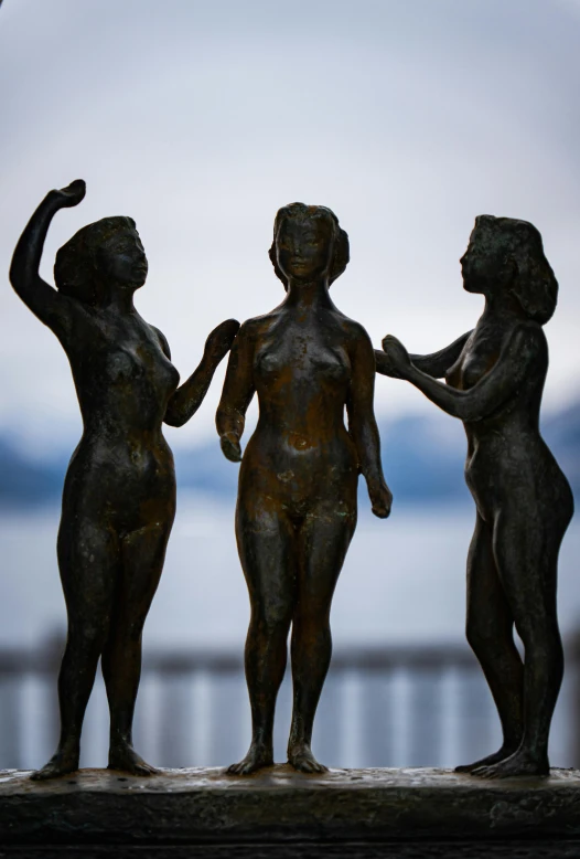 three little  ladies are standing in front of a fence