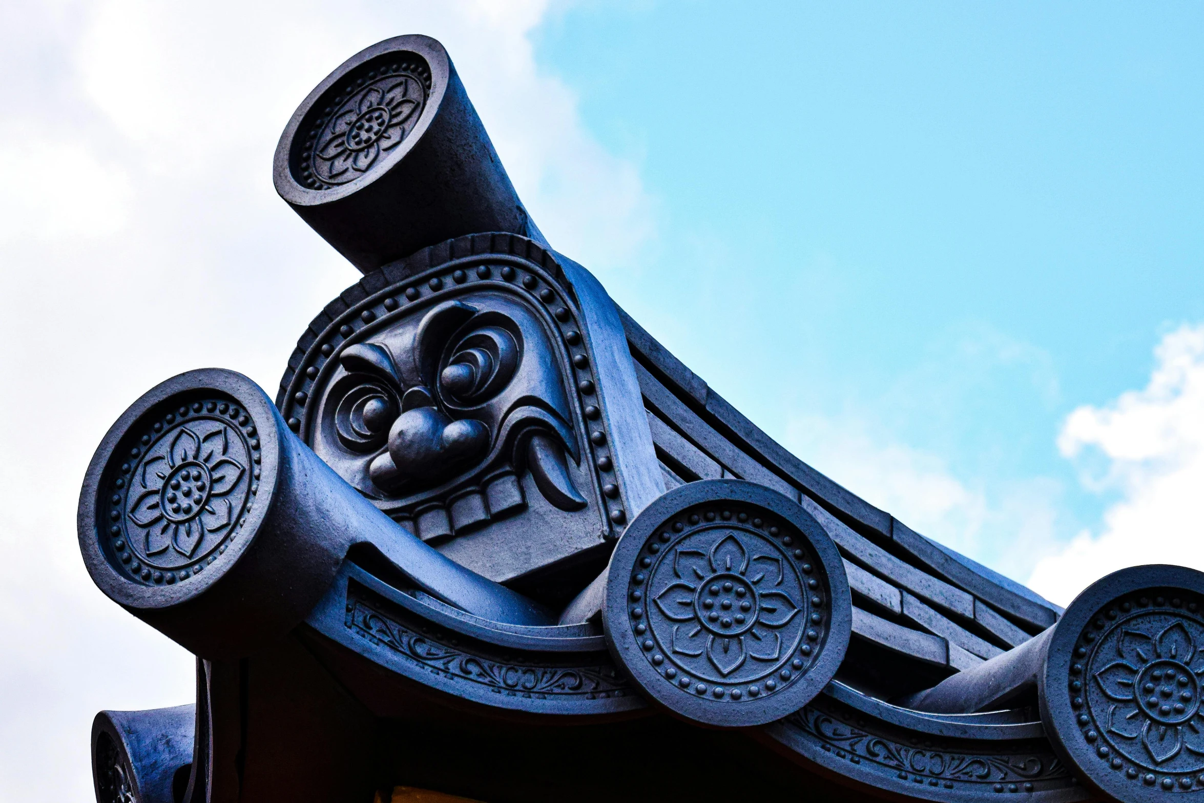 a blue sky with clouds in the background is covered with an artistically designed roof