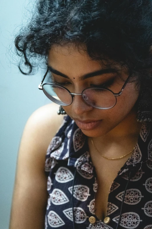 a woman with glasses is looking down at her cellphone