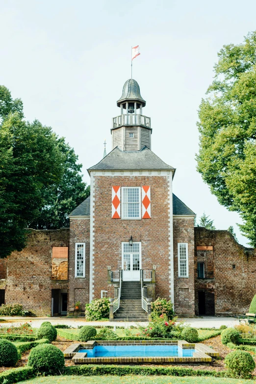 brick house sitting next to a pond and garden