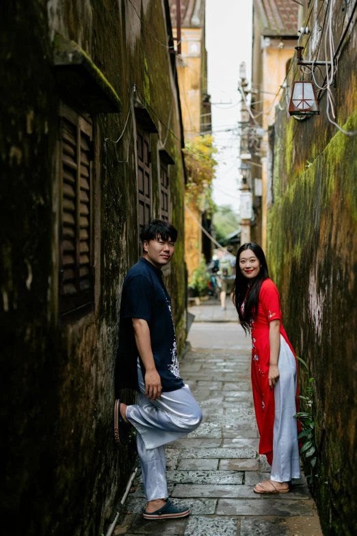 a couple standing together in an alley way with an alley passing by