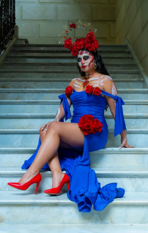 a woman wearing blue dresses sitting on some steps