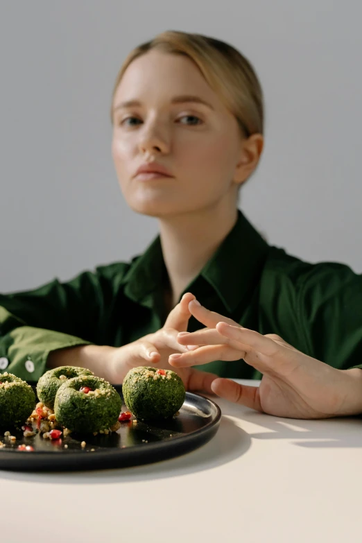 a woman wearing green and sitting down near a plate of dessert