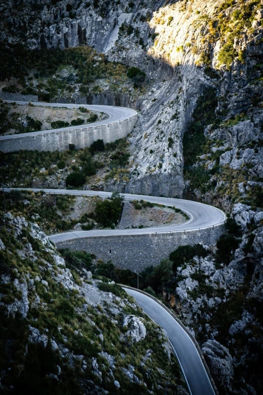 a winding mountain road surrounded by rocks and bushes