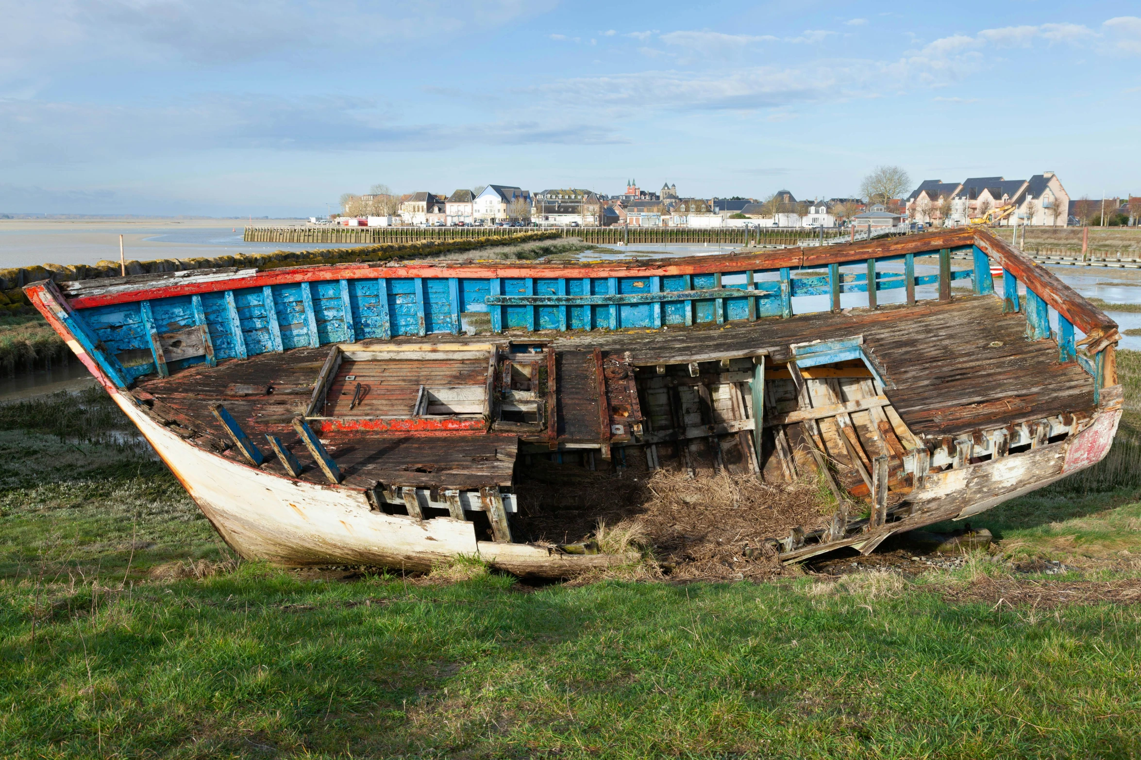a boat that has fallen apart near the grass