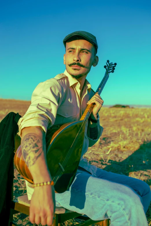 the man sits in a chair holding a musical instrument