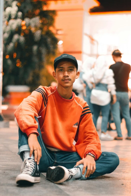 a man sitting on the ground with a baseball cap