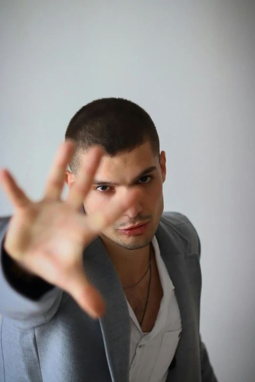 a man in a suit shows a hand sign with both hands