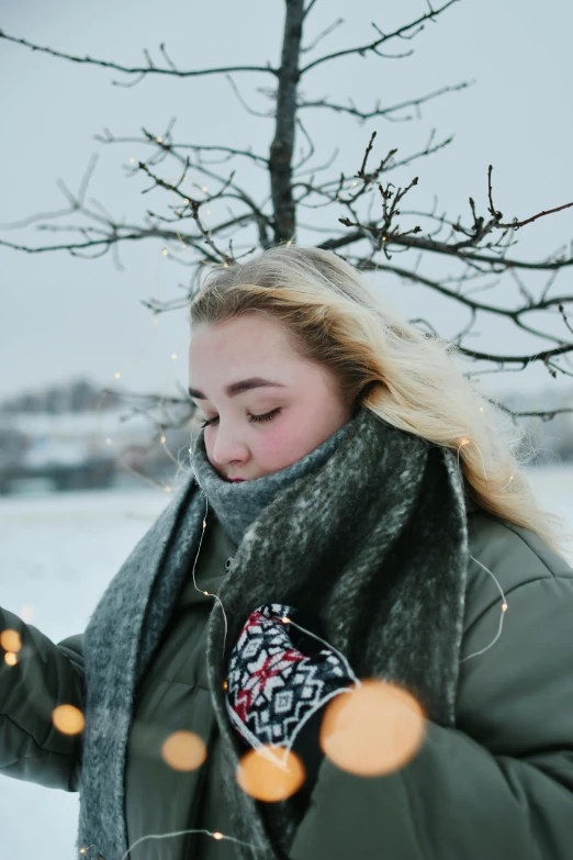 a young woman stands in a snowy area with her lights on