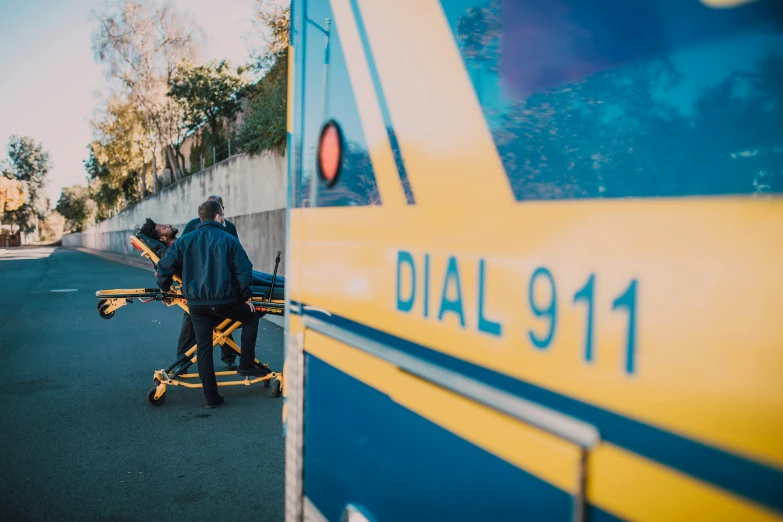 two men loading a bicycle on the side of a yellow bus