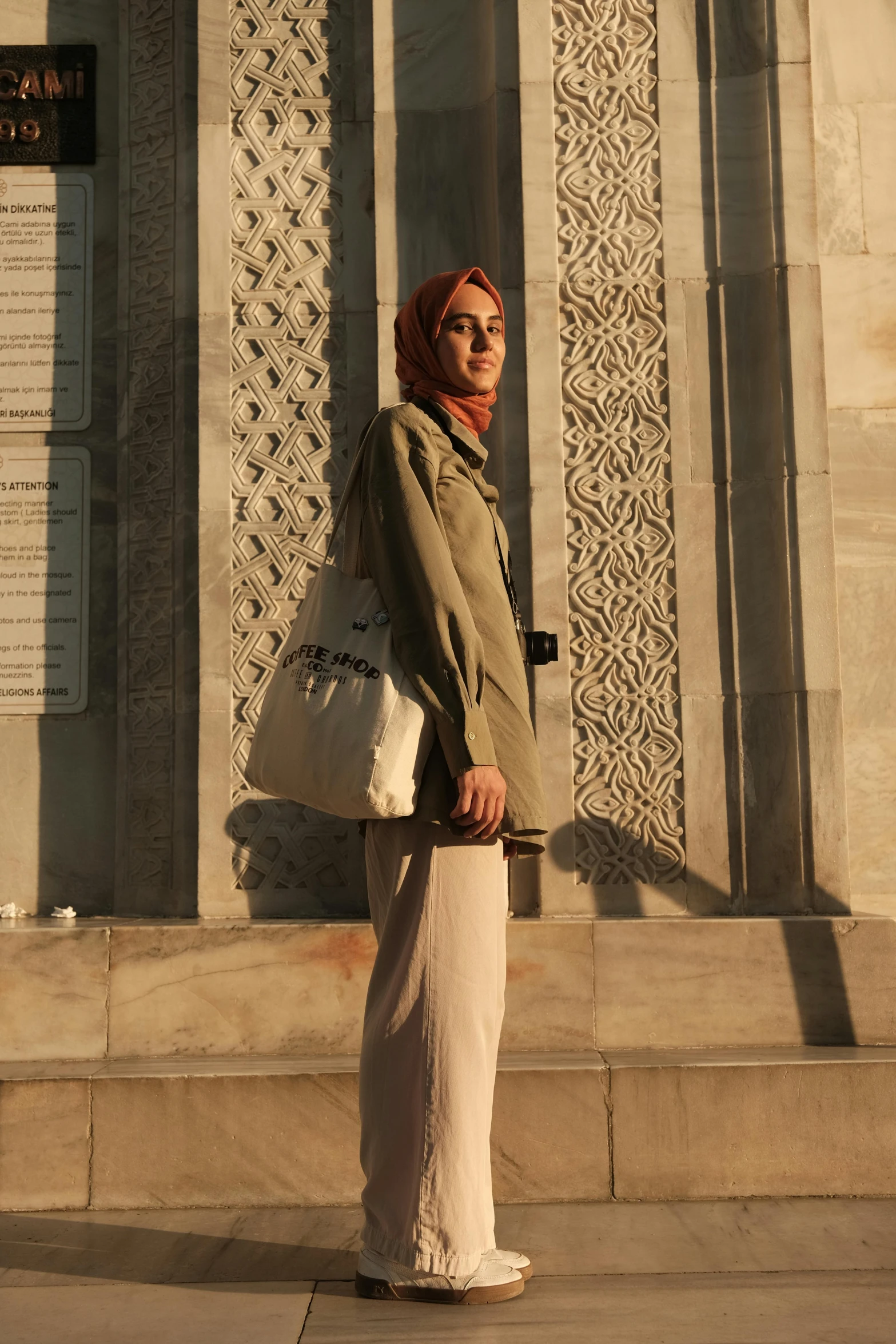 an indian woman holding a white bag and standing in front of a wall