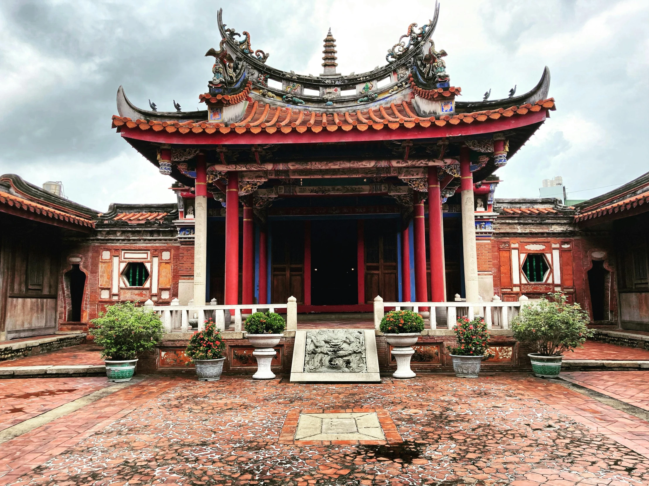 a red asian style building with green shrubs