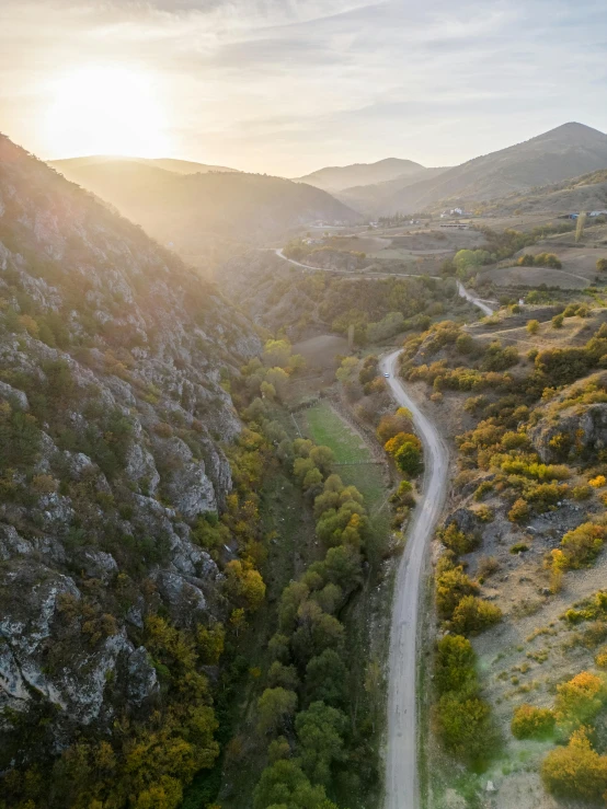 the sun is shining over a hilly country road