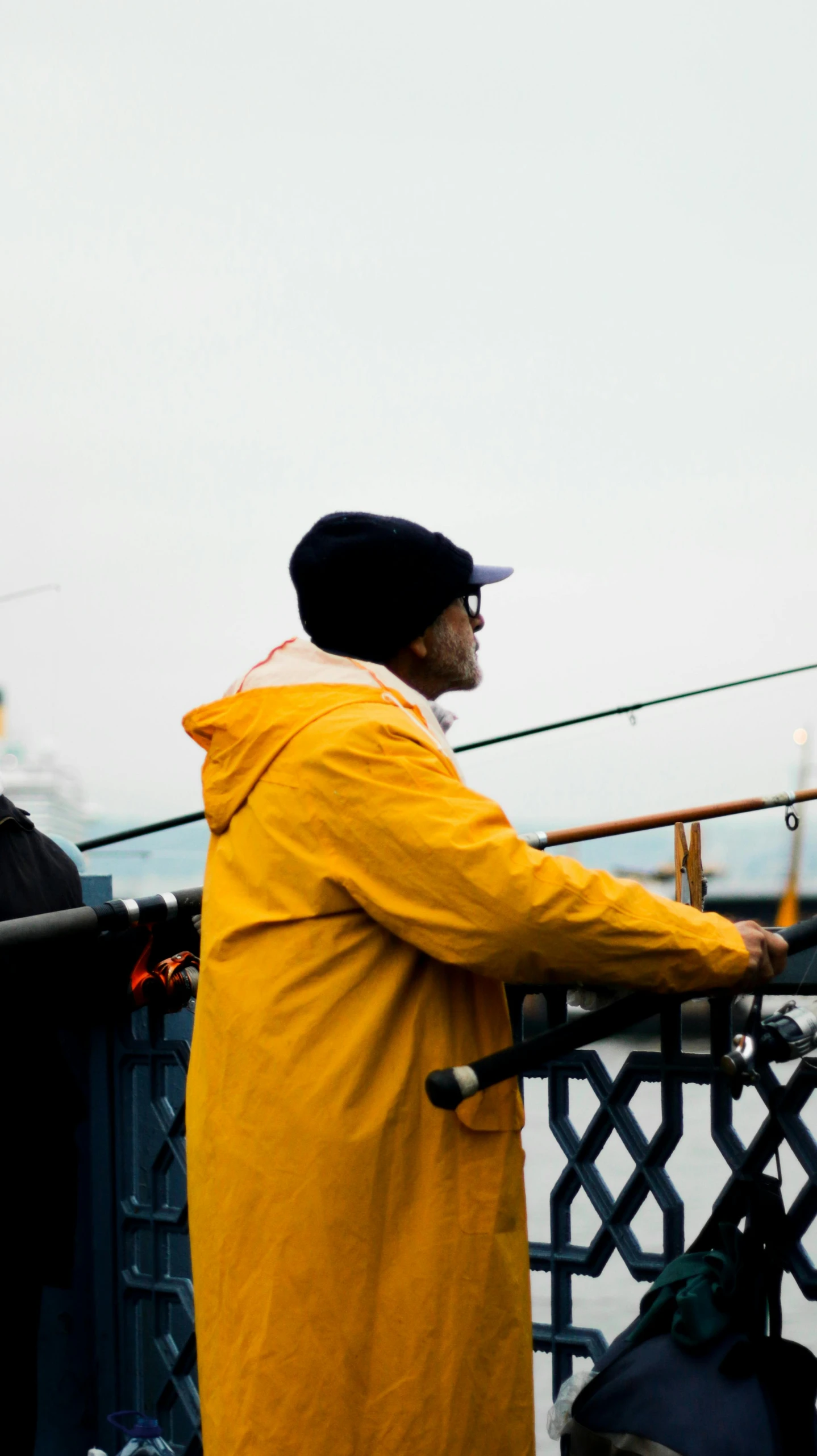 a man standing next to a metal fence near the water