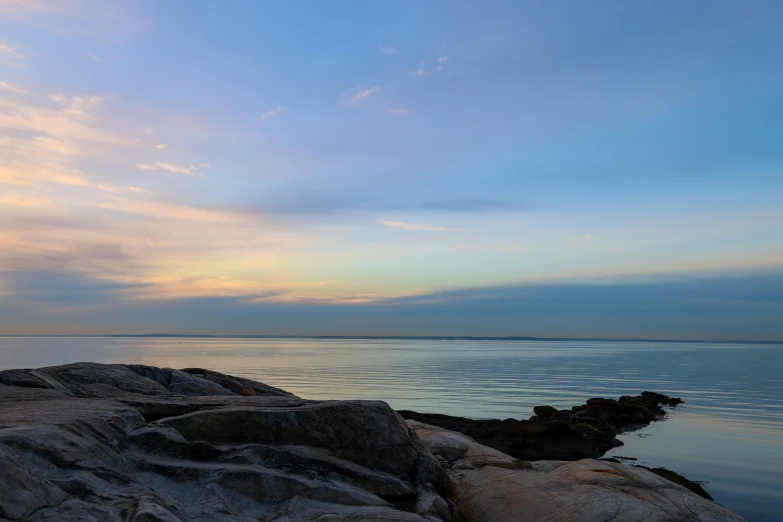 a lone bench sitting on the edge of rocks overlooking the ocean