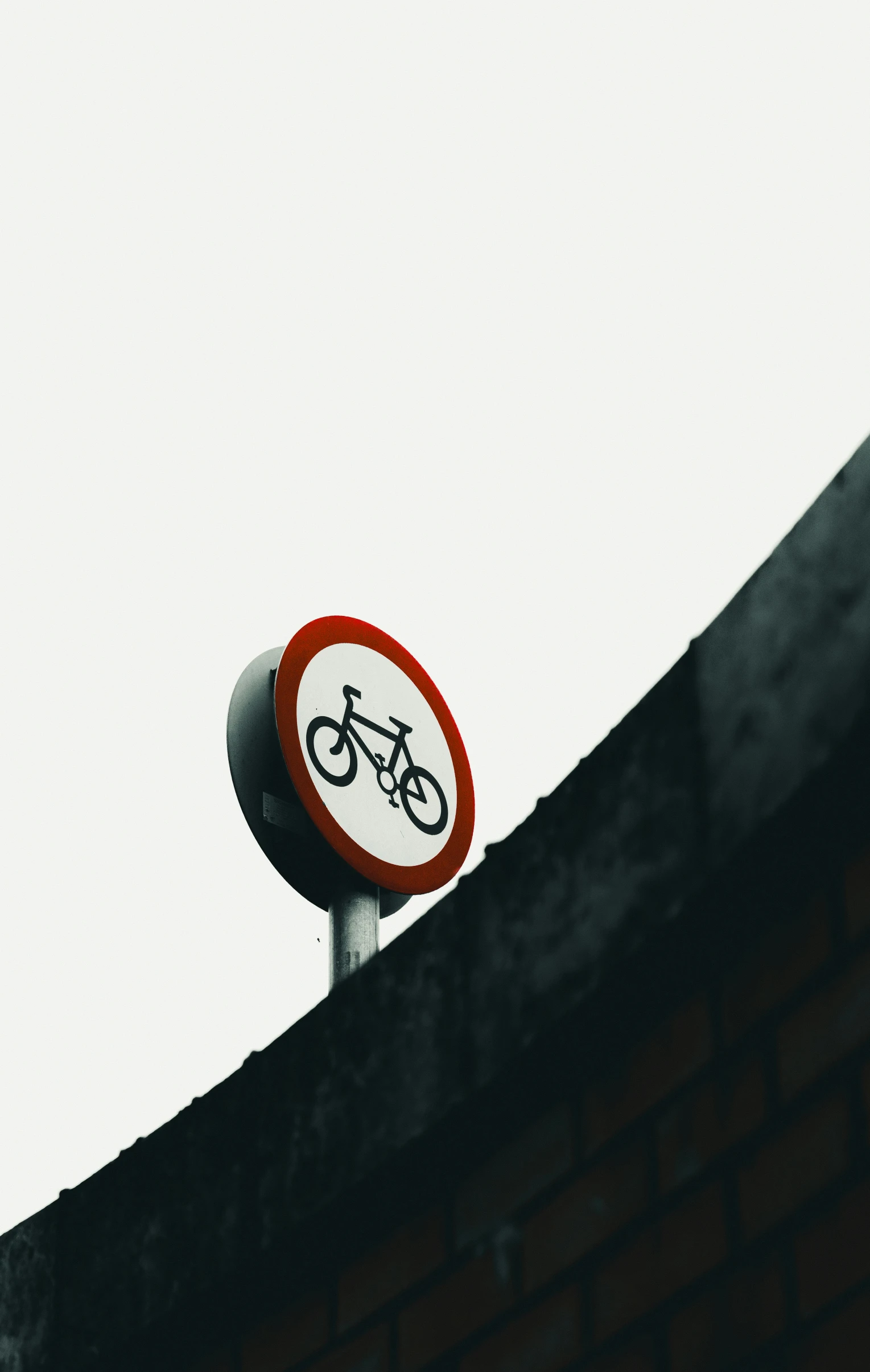 a bicycle sign sitting on top of a brick wall