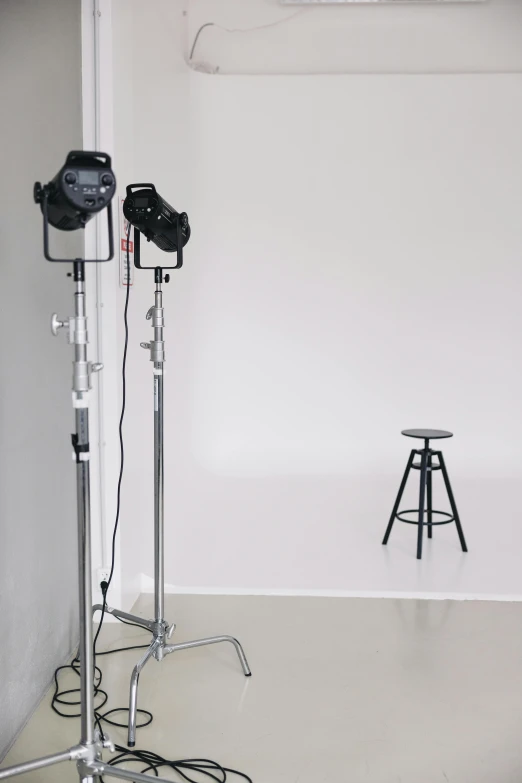 a camera and a tripod in the corner with one stool