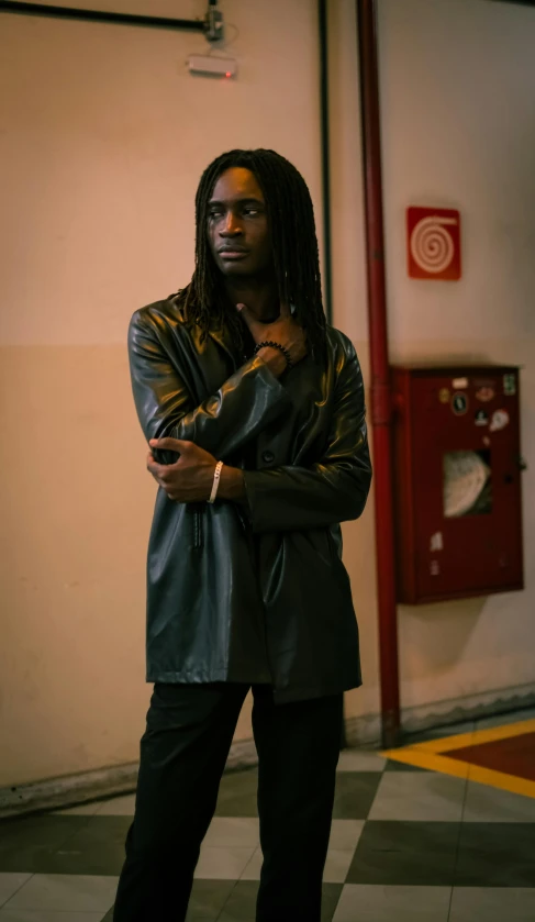 man with dreadlocks standing in a building leaning on the wall